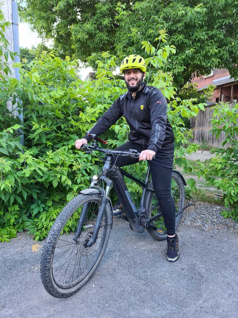 Happy cyclist posing with bike outdoors.