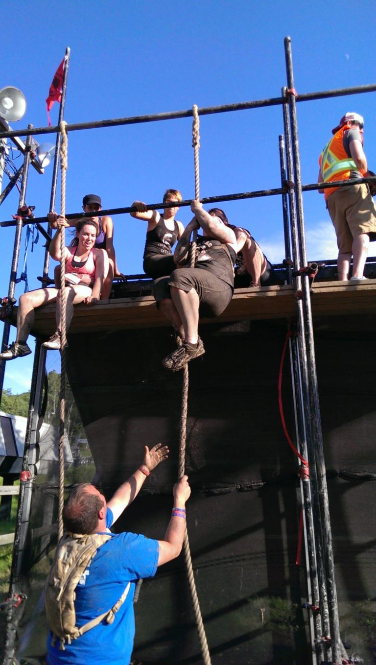 Participants climbing obstacle at outdoor challenge event