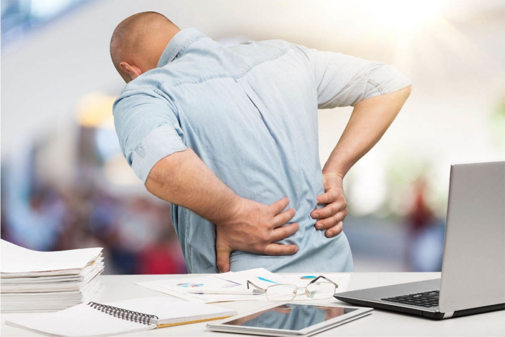 Man experiencing lower back pain at work desk.