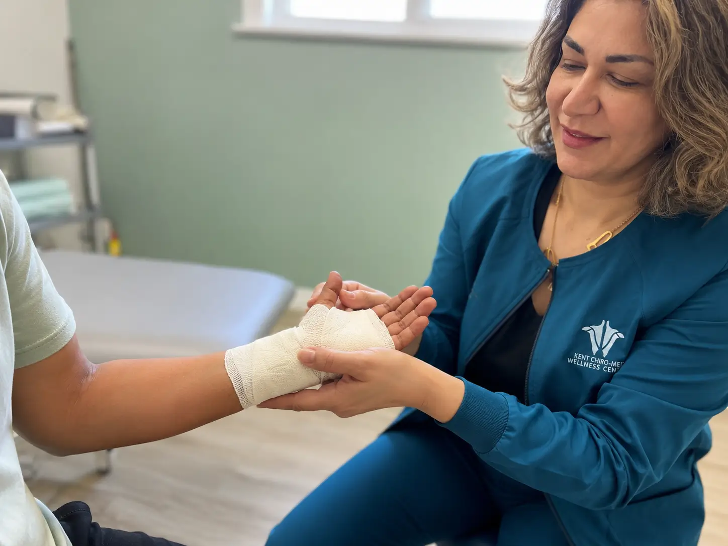Practitioner examining and supporting a patients bandaged hand during carpal tunnel treatment in Ottawa